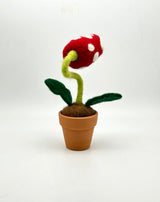 Needle felted plant in pot with red and white dotted head, white eyes and white teeth, from the back