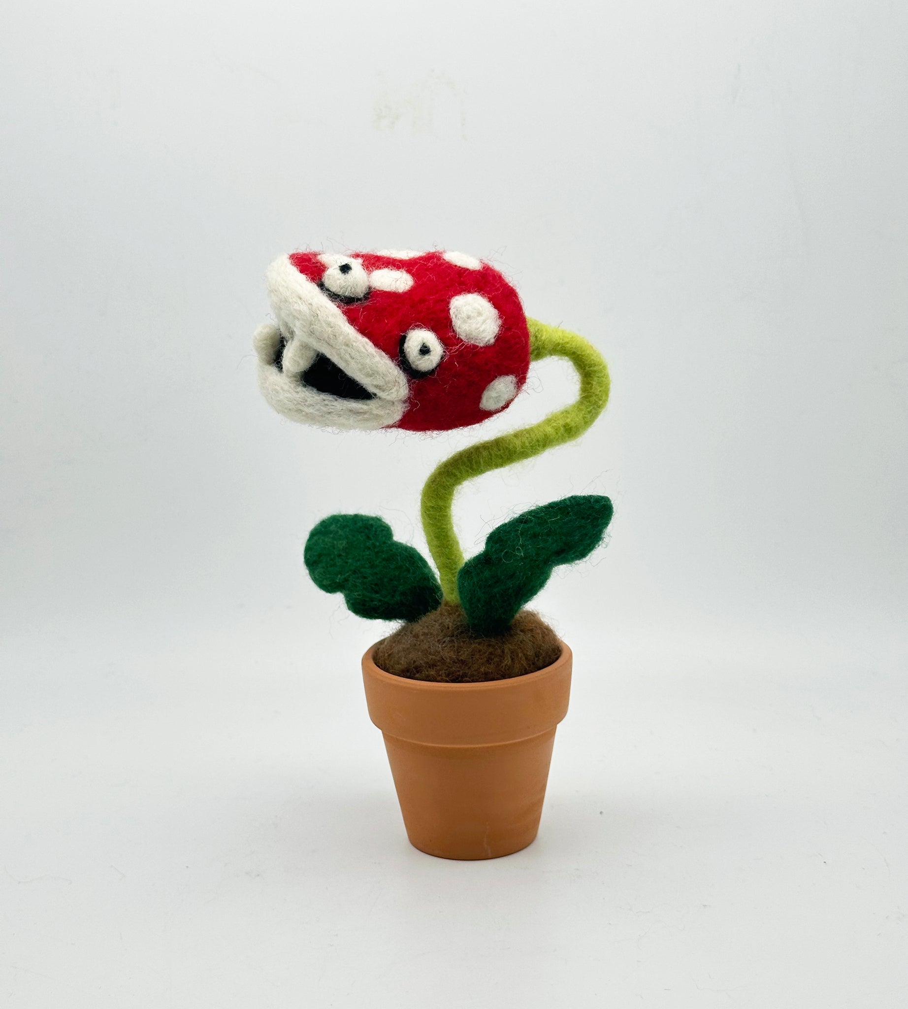 Needle felted plant in pot with red and white dotted head, white eyes and white teeth