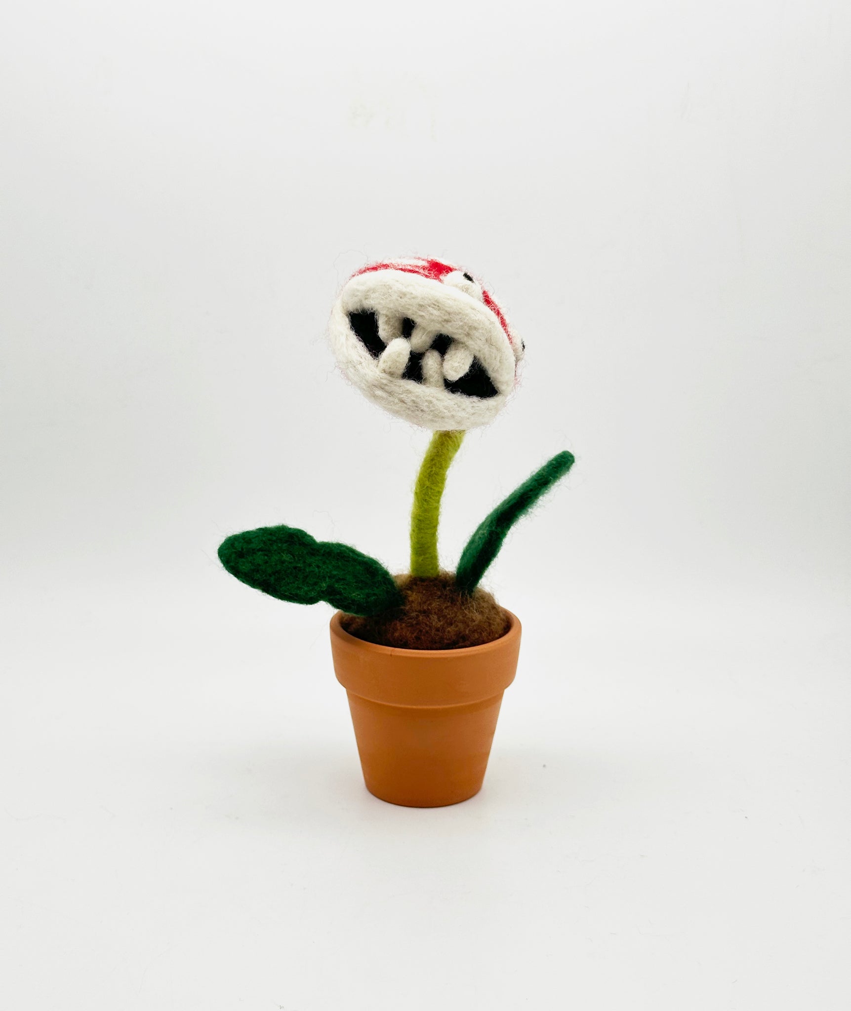 Needle felted plant in pot with red and white dotted head, white eyes and white teeth